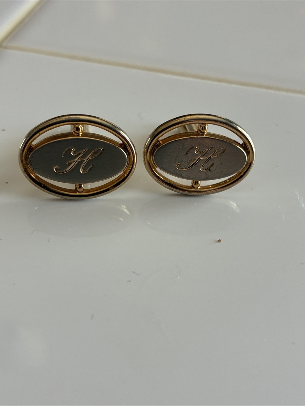 Gold tone cuff links with initial “H”